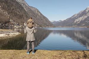 padre e figlio godendo montagne, neve, lago, bene tempo atmosferico, blu cielo, sole. poco ragazzo e il suo padre la spesa tempo insieme. famiglia volta. bellissimo paesaggio. turismo, vacanza, viaggio. sorprendente Visualizza. foto