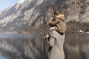 padre e figlio godendo montagne, neve, lago, bene tempo atmosferico, blu cielo, sole. poco ragazzo e il suo padre la spesa tempo insieme. famiglia volta. bellissimo paesaggio. turismo, vacanza, viaggio. sorprendente Visualizza. foto