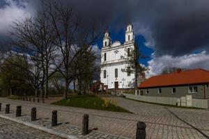 un' bianca cattolico Chiesa su un' estate giorno con buio nuvole nel il sfondo foto