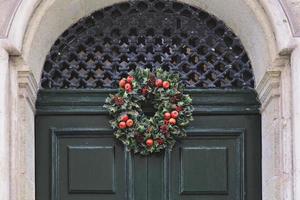 tradizionale verde e rosso Natale ghirlanda sospeso su Ingresso porta di Casa foto