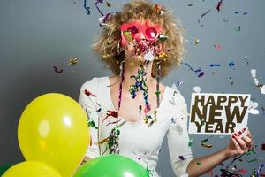 bellissimo donna festeggiare nuovo anno con coriandoli e Tenere cartello. foto