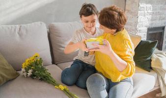 avvicinamento di un' figlio dando il suo madre un' presente e congratularsi sua su vacanze.madre o Da donna giorno concetto foto