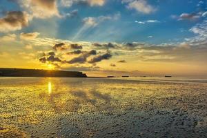 panoramico Visualizza di giallo tramonto su il spiaggia di Arromanches-les-Bains nel Normandia, Francia foto