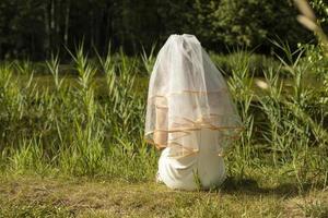 sposa su riva di lago. ragazza nel nozze vestito nel parco. bianca vestito su ragazze. velo su testa. foto