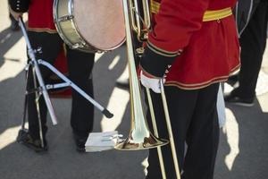 orchestra membro detiene ottone tubo. trombettista particolari. cerimoniale rosso uniforme. foto
