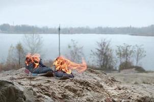 ardente gli sport scarpe da ginnastica o Palestra scarpe su fuoco In piedi su sabbioso spiaggia costa. atleta bruciato fuori. fisico sforzo durante formazione concetto foto