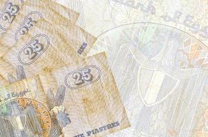 25 egiziano piastre fatture bugie nel pila su sfondo di grande semi trasparente banconota. astratto attività commerciale sfondo foto