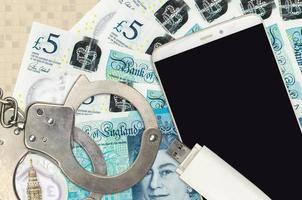 5 Britannico sterline fatture e smartphone con polizia manette. concetto di gli hacker phishing attacchi, illegale truffa o il malware morbido distribuzione foto