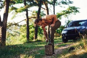 tagliaboschi con un ascia taglio Di legno. bello A petto nudo uomo con muscolare corpo genere è nel il foresta a giorno foto