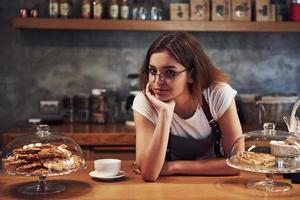 pendente su il di legno tavolo. giovane femmina bar lavoratore al chiuso. concezione di attività commerciale e servizio foto