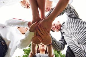 vicino su Visualizza di mani di il giovane squadra di riuscito amici all'aperto foto