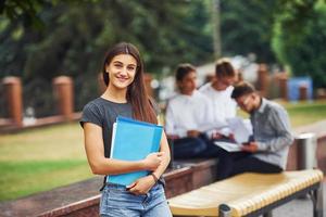 ragazza con blu cartella nel mani. gruppo di giovane studenti nel casuale Abiti nel il città a giorno foto