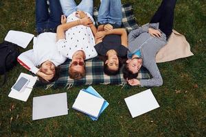 avendo bene riposo. gruppo di giovane studenti nel casuale Abiti su verde erba a giorno foto