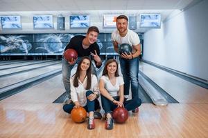 Buone vacanze. i giovani amici allegri si divertono al bowling club durante i fine settimana foto