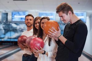 facendo una faccia buffa. i giovani amici allegri si divertono al bowling club durante i fine settimana foto