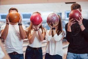 palline con numeri diversi su di esso. i giovani amici allegri si divertono al bowling club durante i fine settimana foto