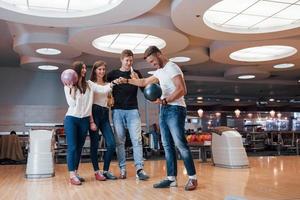 bel gioco. i giovani amici allegri si divertono al bowling club durante i fine settimana foto