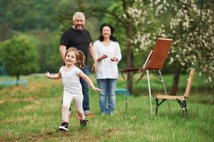 divertente bambino felice. nonna e nonno si divertono all'aperto con la nipote. concezione della pittura foto