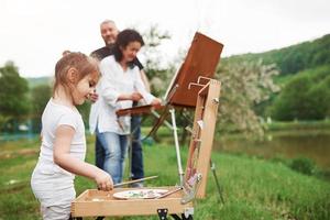 tempo nuvoloso. nonna e nonno si divertono all'aperto con la nipote. concezione della pittura foto