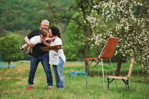 atmosfera calma e tranquilla. nonna e nonno si divertono all'aperto con la nipote. concezione della pittura foto