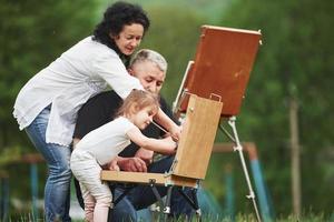 tutti sono in processo. nonna e nonno si divertono all'aperto con la nipote. concezione della pittura foto