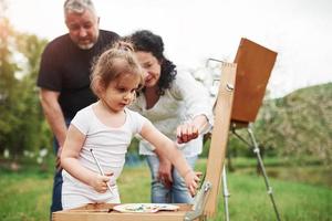 prendi un altro colore per questo. nonna e nonno si divertono all'aperto con la nipote. concezione della pittura foto