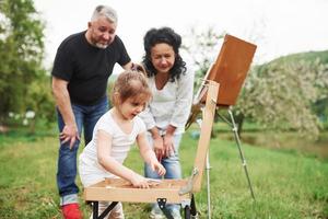 so cosa fare. nonna e nonno si divertono all'aperto con la nipote. concezione della pittura foto