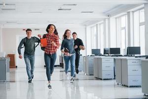 correndo in avanti. gruppo di giovani che camminano in ufficio durante la pausa foto
