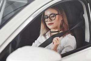 sicurezza primo. donna nel ufficiale Abiti provando sua nuovo auto nel automobile salone foto