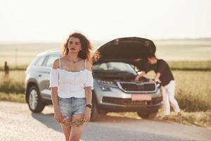 sfocato sfondo. uomo riparazione auto di ragazza con Riccio capelli. meccanico assistenza foto