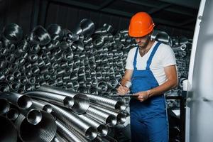 ispezione nel progresso. uomo nel uniforme lavori su il produzione. industriale moderno tecnologia foto