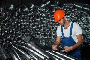 con il computer portatile su il tubi. uomo nel uniforme lavori su il produzione. industriale moderno tecnologia foto