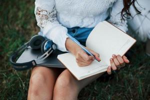 processi di scrivere. giovane donna avere fine settimana e si siede nel il parco a giorno foto