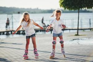 Due carino bambini equitazione di rullo pattini nel il parco a giorno foto