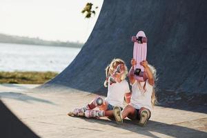 provando nuovo pattinare. Due carino femmina bambini avere divertimento all'aperto nel il parco foto