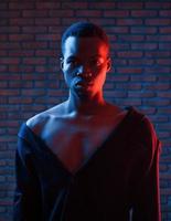 verticale foto. futuristico neon illuminazione. giovane africano americano uomo nel il studio foto