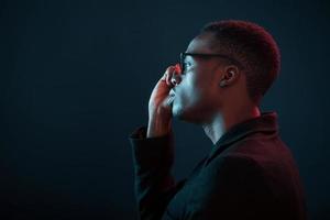 moda modello. futuristico neon illuminazione. giovane africano americano uomo nel il studio foto