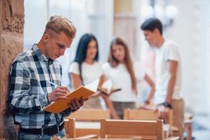 tipo legge il suo bloc notes. quattro giovane studenti nel casuale Abiti avere incontro a piovoso giorno foto