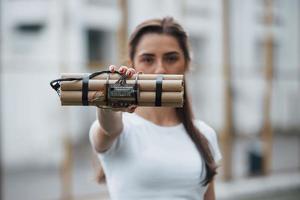 mostrando tempo bomba. giovane donna Tenere pericoloso esplosivo arma nel mano foto