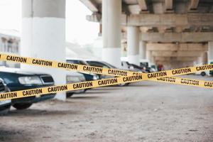 grande la zona. giallo attenzione nastro vicino il auto parcheggio lotto a giorno. crimine scena foto