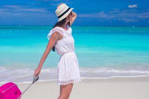 donna che cammina con i suoi bagagli su una spiaggia foto