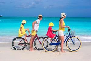 giovani genitori e bambini che vanno in bicicletta su una spiaggia foto