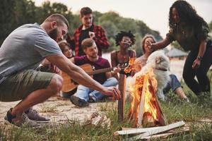 estate felicità. gruppo di persone avere picnic su il spiaggia. amici avere divertimento a fine settimana tempo foto