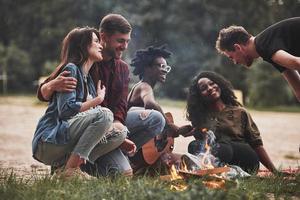 io voglio raccontare voi qualche cosa. gruppo di persone avere picnic su il spiaggia. amici avere divertimento a fine settimana tempo foto