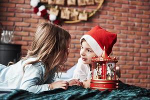 fissando a ogni Altro. bambini è giocando con giocattolo giostra nel il nuovo anno volta. uno ragazza è con Santa cappello su testa foto