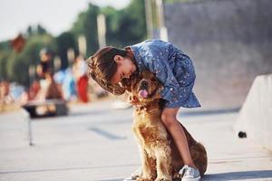 nel amore con sua animale domestico. carino poco ragazza avere un' camminare con sua cane all'aperto a soleggiato giorno foto