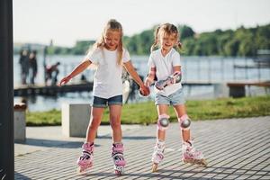 Due carino bambini equitazione di rullo pattini nel il parco a giorno foto