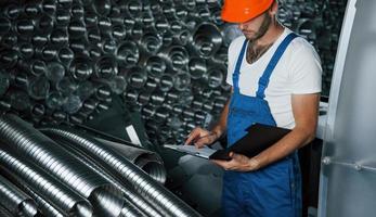 molti di ventilazione tubi. uomo nel uniforme lavori su il produzione. industriale moderno tecnologia foto