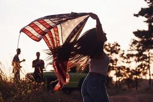 si sente libertà. amici avere simpatico fine settimana all'aperto vicino il loro verde auto con Stati Uniti d'America bandiera foto