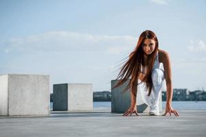 pronto per il correre. tiro di allegro donna fare fitness esercizi vicino il lago a giorno foto